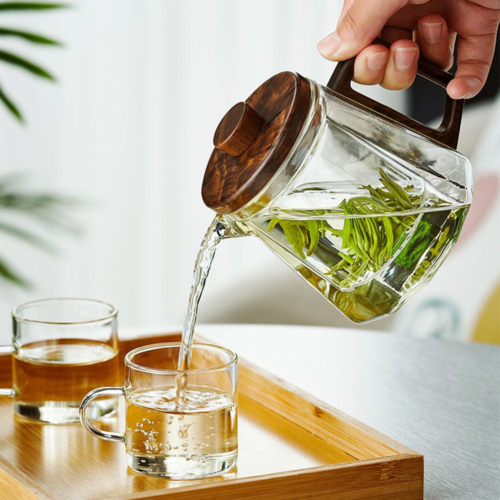 Thee schenken met de glazen theepot met walnoothouten handgreep; kopjes niet inbegrepen